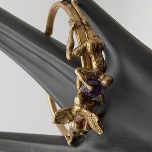 Unusual cuff bracelet.  Two creatures disputing over purple  ball.  Brass.